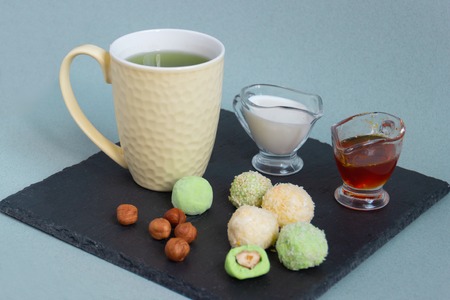 Fat keto peanut butter, cheesecake, matcha balls and keto matcha coconut bulletproof tea in yellow cup. keto protein balls and matcha tea recipes ingredients. it works ketogenic diet. blue background.の写真素材