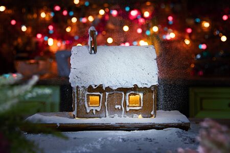 Gingerbread house sprinkled with icing sugar like snow. The spirit of Christmas. Garland on the backgroundの写真素材