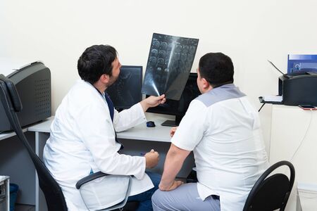 Two young doctors looking at patient's brain scanning. Medical consultation discuss MRI image.の写真素材