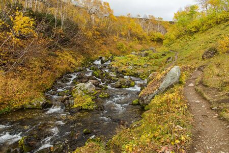 River in mountains, rocks in water. Beautiful golden autumn landscape in Kamchatka near Vachkazhetz...