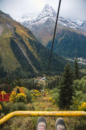 Dombay ski resort from the cableway chairelift, beautiful mountains landscape, small village and large snowy peaks in autumn season, shues of traveler details, Caucasus, Russiaの写真素材
