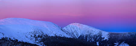 Mountain ridge in the sunset, snowy peaks Studnicni and Snezka mountain are colored with blue light after sunset. Winter Time in Krkonose National Park - the highest point in the Czech Republic is Snezka.の写真素材