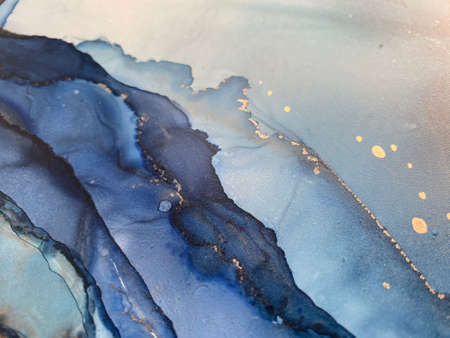 Abstract blue background with beautiful smudges and stains made with alcohol ink and gold pigment. Blue colored fragment with texture resembles watercolor or aquarelle painting.の写真素材