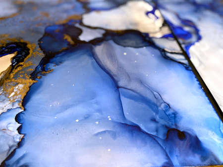 Abstract blue art background with beautiful smudges and stains made with alcohol ink and gold pigment. Fragment of art with blue fluid texture resembles watercolor or aquarelle painting.の写真素材