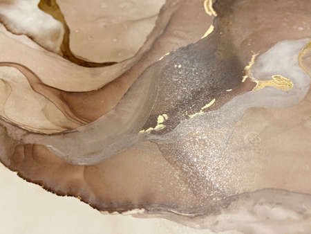 Abstract beige-brown background with gold, beautiful smudges and stains made with alcohol ink and gold pigment. Fragment of art with beige texture resembles marble, watercolor or aquarelle painting.の写真素材