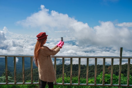 Woman hiker taking photo with cellphone at mountain