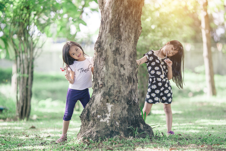 Two little girls relaxing play in the park and eat lollipops.の写真素材