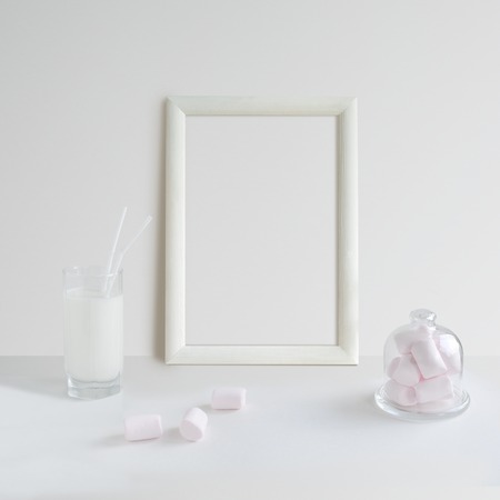 Mock up with white wooden Frame, glass of milk and pink marshmallow on white backgroundの写真素材