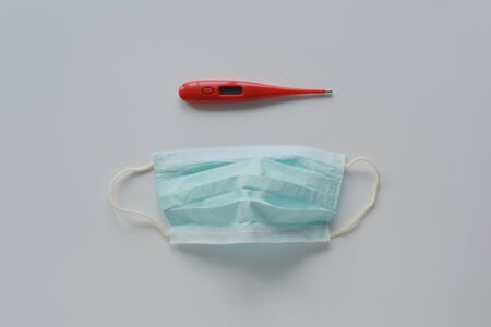 Medical electronic thermometer and medical face mask for protection infection on white background.