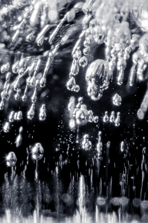 Close up of bubbles trapped in an ice cube creating glowing metallic looking dropsの写真素材