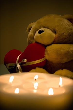 Valentine's Teddy bear holding a heart behind the candlesの写真素材