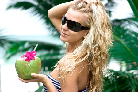 Girl holding coconut and palm on the backgroundの写真素材