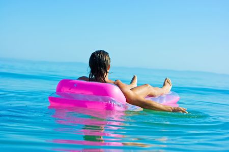 Handsome muscular young man floating on inflatable raft in sea waterの写真素材
