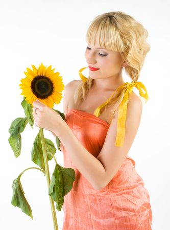 Close-up beautiful fresh young blonde smiling with sunflower with bright make-up in studio shotの写真素材