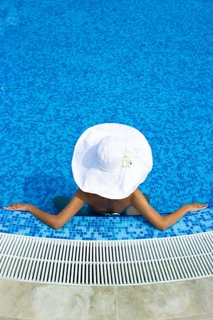 Woman with white hat sitting in the swimming poolの写真素材