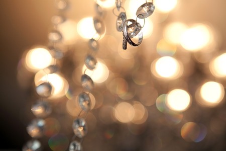 Wedding rings hanging on crystal stripe with bokeh as backgroundの写真素材