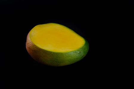 Sliced juicy ripe natural mango isolated on dark backgroundの写真素材