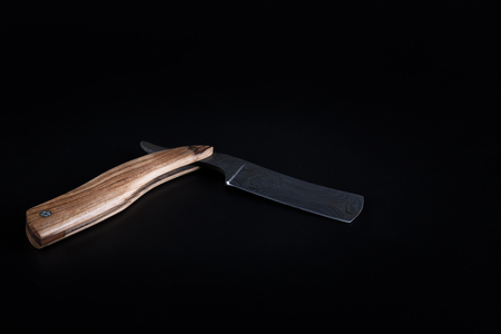Cut throat razor forged by damascus steels with natural wood handle isolated on a dark backgroundの写真素材