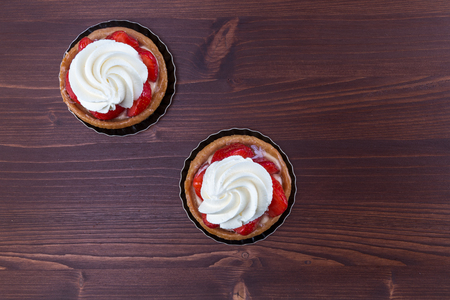 Two delicious strawberry tarts with chantilly cream - tartellete - on an ipe natural wood table - top viewの写真素材