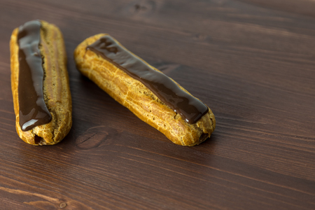 Two gorgeous asymmetric french chocolate eclairs on an ipe dark brown natural wood tableの写真素材