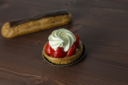 Delicious strawberry tarts with chantilly cream - tartellete - and Chocolate eclair on an ipe...