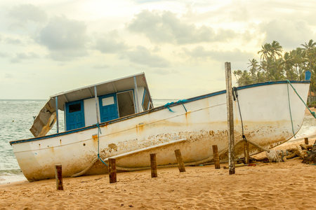 Old vintage blue and white boat on the shore of a tropical beach in south americaの写真素材