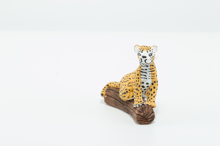 Jaguar, yellow, black and white spots, seated on a wood trunk isolated in white backgroundの写真素材