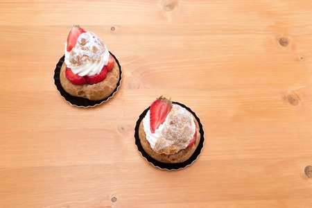 Chou aux fraises - Tart with strawberries and whipped cream. Top view on a oak tableの写真素材