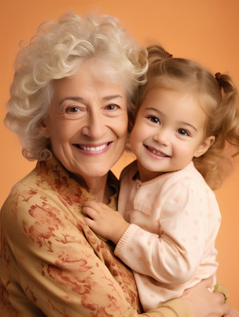 Portrait of happy senior woman with her granddaughter on orange background.の素材