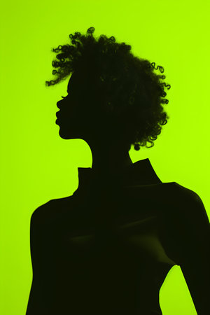 Silhouette of a woman with afro hairstyle on green backgroundの素材