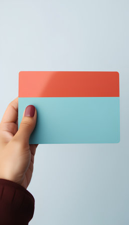 Female hand holding a business card with a blue and red background.の素材