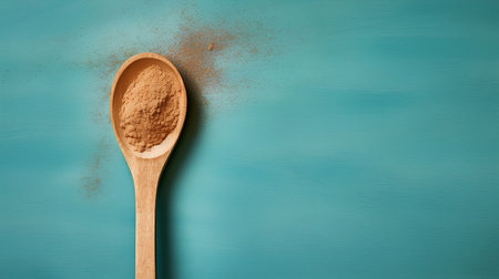 Cinnamon powder in a wooden spoon on a turquoise backgroundの素材