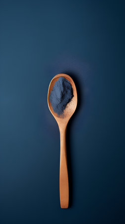 Moringa powder in a wooden spoon on a blue background.の素材