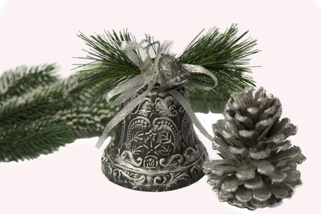 Silver christmas bell with a silver bump and a snow-covered fir-tree branch.の写真素材