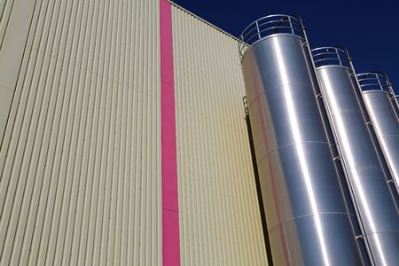 Stainless steel silos in the chemical industry, bulk plastics silo against a blue skyの写真素材