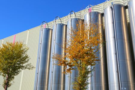 Stainless steel silos in the chemical industry, bulk plastics silo against a blue sky