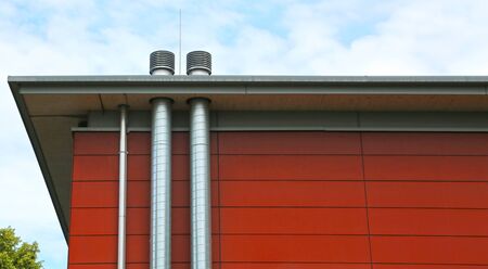 Red exterior wall of a modern building with ventilation pipes.   の写真素材