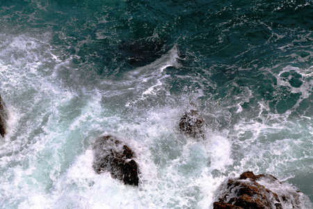 Sea, wave, white foam, coastal stones in background