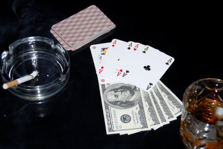 Play cards, ashtray, money and glass of whiskey on a black backgroundのeditorial素材