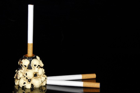 White cigarette in a candlestick decorated with human skullsの写真素材