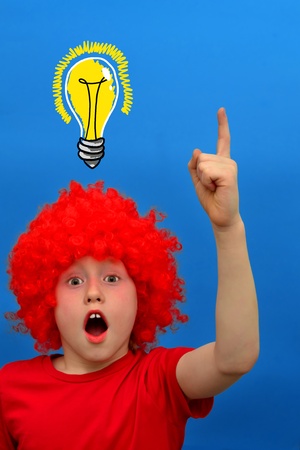 Funny boy in red curly wig makes discoveryの写真素材