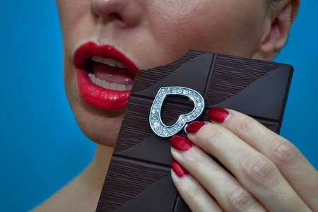 Dangerous woman intending to eat diamond heart with dark chocolate barの写真素材