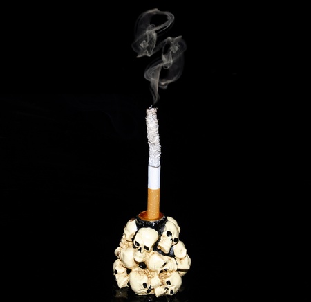 White cigarette in a candlestick decorated with human skullsの写真素材