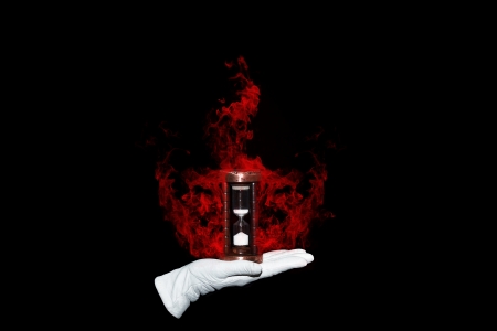 Illusionist holds burning hourglass symbolizing burning time