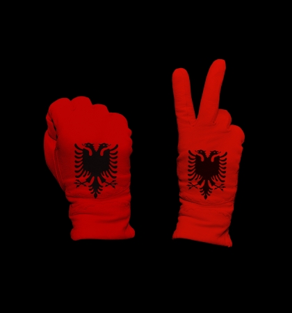 Clenched fist in leather glove, and hand with victory gesture in a glove decorated with Albania flagの写真素材