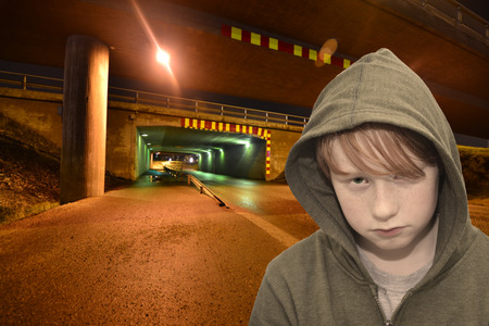sad redhead boy standing on a lonely dark streetの写真素材