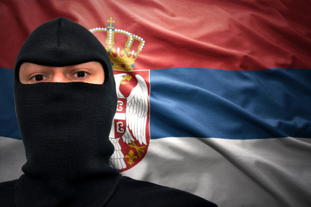 dangerous man in a mask on a serbian flag backgroundの写真素材