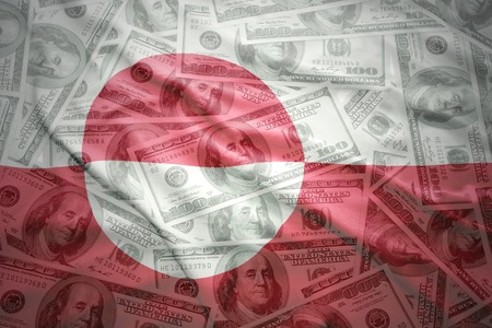 colorful waving greenlandic flag on a american dollar money backgroundの写真素材