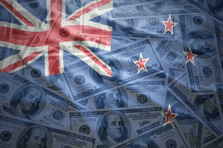 colorful waving new zealand flag on a american dollar money backgroundの写真素材