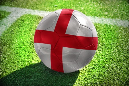 football ball with the national flag of england lies on the green field near the white lineの写真素材